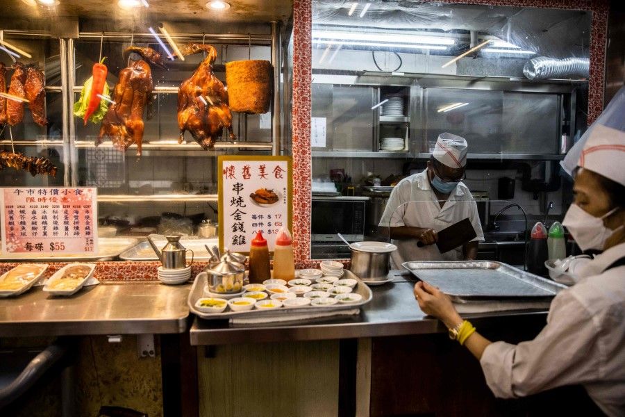 A cook prepares roast duck at an eatery in Hong Kong, 8 June 2023. (Isaac Lawrence/AFP)