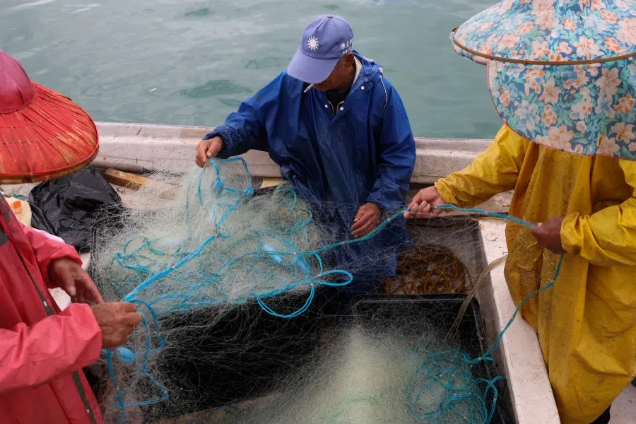Fishermen work on their boat docked at a port in Kinmen, Taiwan, on 21 February 2024. (Ann Wang/Reuters)