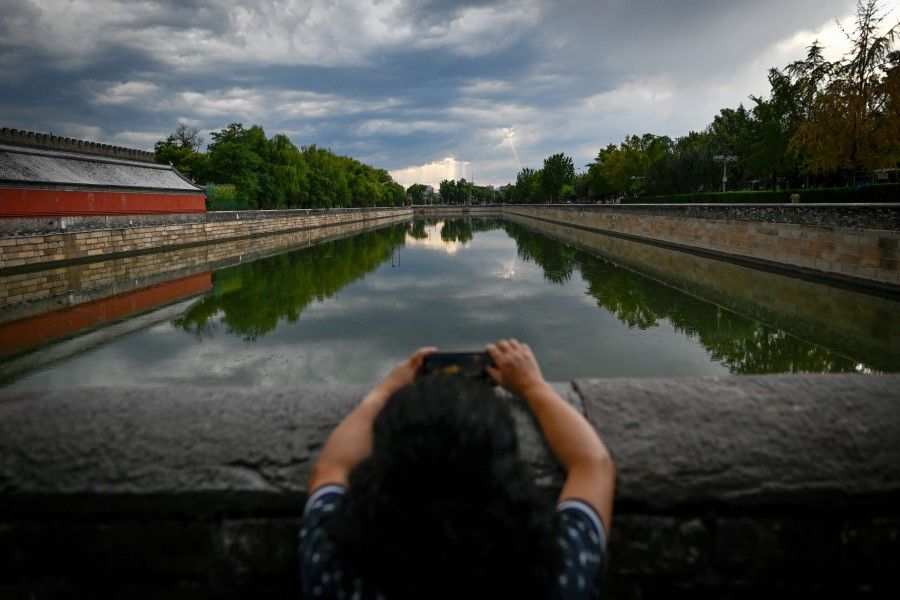 A woman uses her mobile phone to take pictures at the Forbidden City in Beijing on 1 September 2020. (Wang Zhao/AFP)