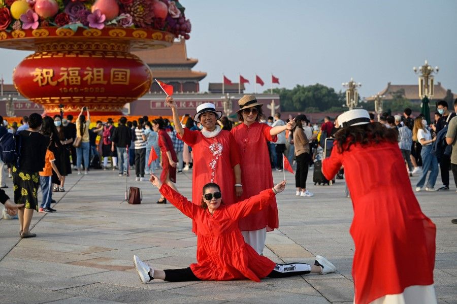 People pose for photos in front of an installation celebrating the upcoming National Day and the 20th Communist Party Congress at Tiananmen Square in Beijing on 29 September 2022. (Jade Gao/AFP)