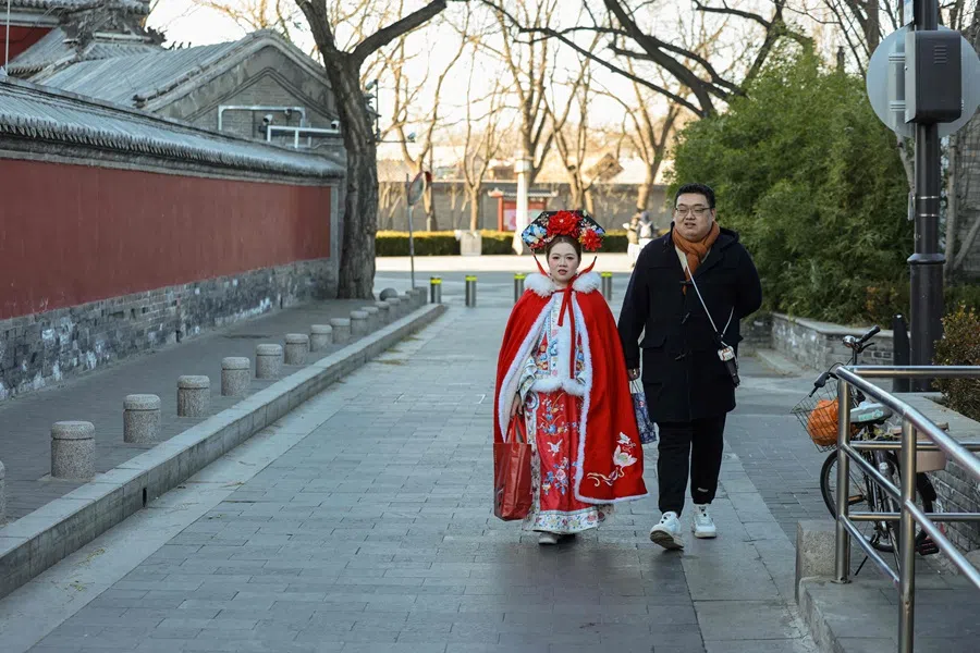 A man walks with a woman wearning a traditional Chinese dress near the Temple of Confucius in Beijing on 2 December 2025. (Ludovic Marin/AFP)