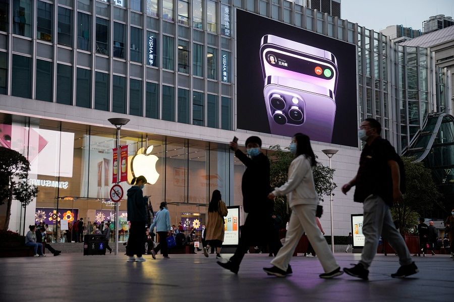 People walk near a display advertising the Apple iPhone 14 outside its store in Shanghai, China, 7 November 2022. (Aly Song/Reuters)