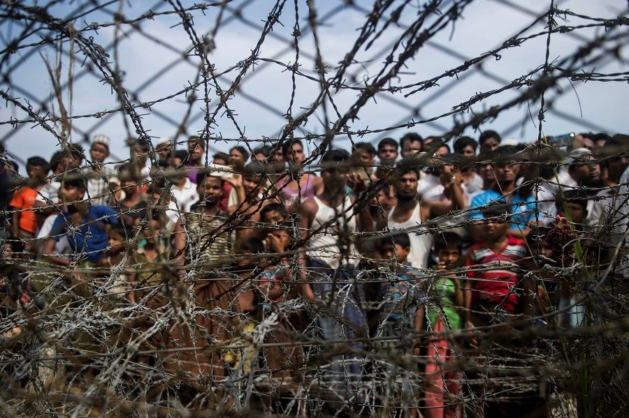 This file photo taken on 25 April 2018 shows Rohingya refugees gathered behind a barbed-wire fence at a temporary settlement setup in a "no man's land" border zone between Myanmar and Bangladesh, near Maungdaw district in Myanmar's Rakhine state. (Ye Aung Thu/AFP)