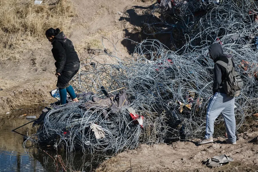 Migrants cross concertina wire laid by the Texas National Guard at the US-Mexico border in Ciudad Juarez, Chihuahua state, Mexico, on 8 February 2024. (Justin Hamel/Bloomberg)