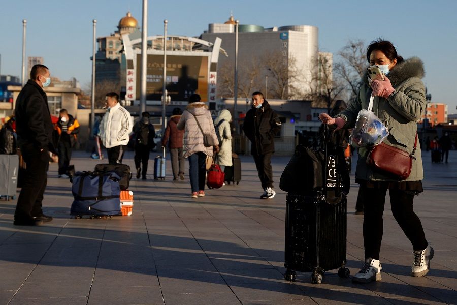 People wearing face masks walk outside Beijing Railway Station as the travel rush starts ahead of the Lunar New Year, also known as the Spring Festival, in Beijing, China, 17 January 2022. (Carlos Garcia Rawlins/Reuters)