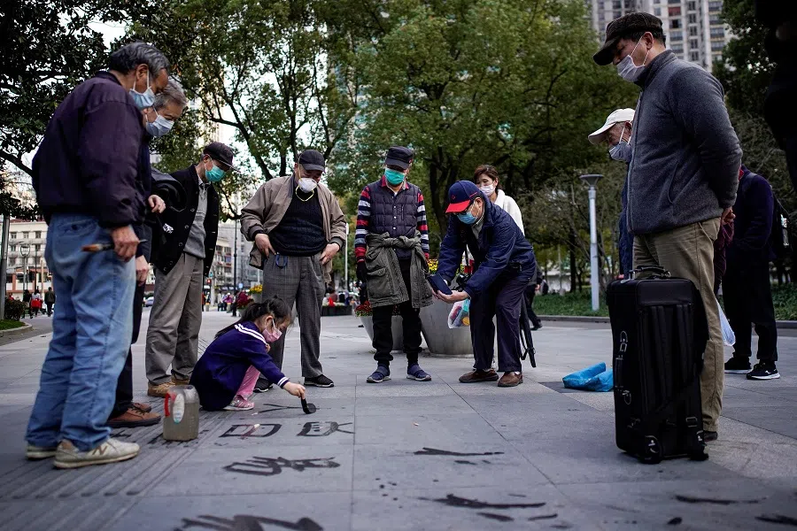 A girl wears a protective face mask as she practises Chinese calligraphy on a street at a park following the outbreak of the Covid-19 coronavirus, in downtown Shanghai, China, on 17 March 2020. (Aly Song/Reuters)