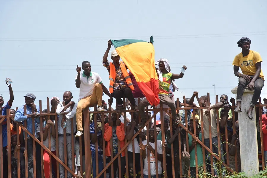 People hold up the Guinea national flag during celebrations as the Guinean Special Forces arrive at the Palace of the People in Conakry, Guinea on 6 September 2021. (Cellou Binani/AFP)