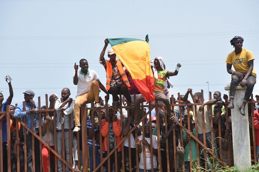 People hold up the Guinea national flag during celebrations as the Guinean Special Forces arrive at the Palace of the People in Conakry, Guinea on 6 September 2021. (Cellou Binani/AFP)