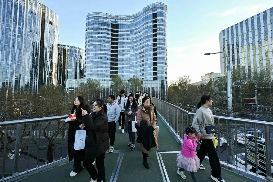 People walk along an overpass at the Sanlitun business area in Beijing on 30 November 2024. (Adek Berry/AFP)