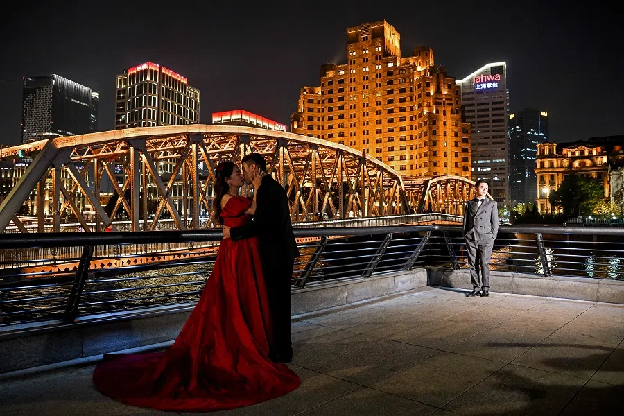 People are seen posing for pictures next to the Garden Bridge of Shanghai, in the Huangpu district in Shanghai on 6 December 2023. (Hector Retamal/AFP)