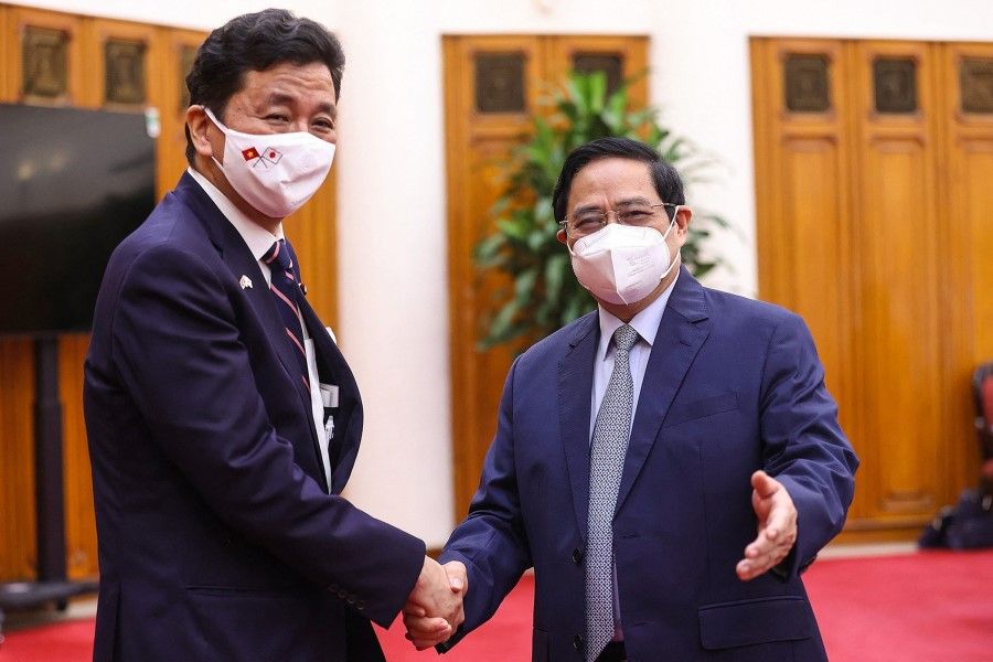 This picture taken and released by the Vietnam News Agency on 12 September 2021 shows Vietnam's Prime Minister Pham Minh Chinh (right) shaking hands with Japan's Defence Minister Nobuo Kishi before a meeting in Hanoi. (STR/Vietnam News Agency/AFP)