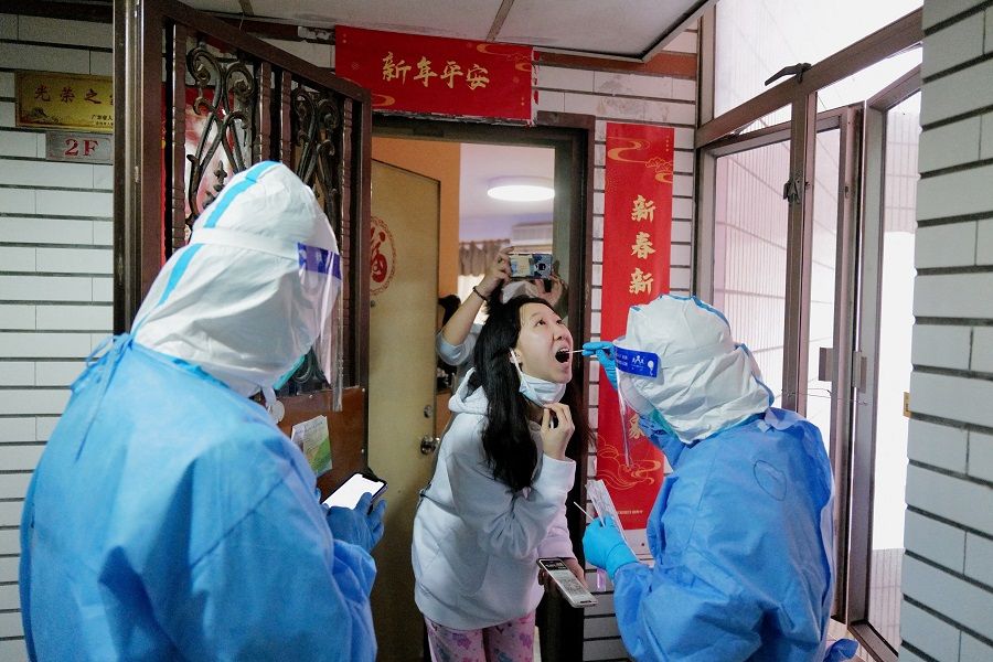 A worker in a protective suit collects a swab from a resident at a residential compound under lockdown, in Shenzhen, Guangdong province, China, 14 March 2022. (CNS photo via Reuters)