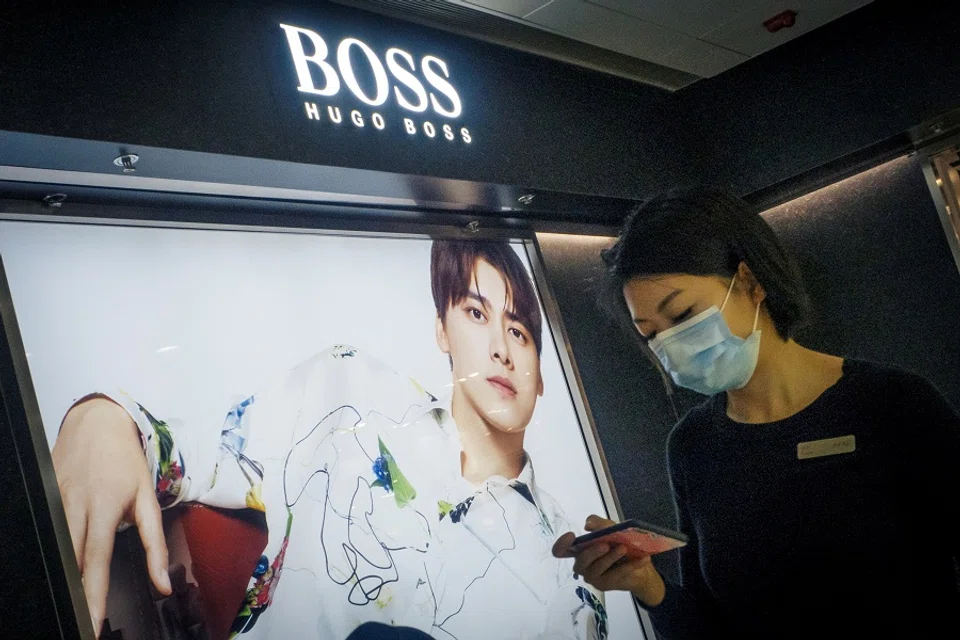 A woman walks past a store of German fashion house Hugo Boss in Beijing, China, 27 March 2021. (Thomas Peter/File Photo/Reuters)