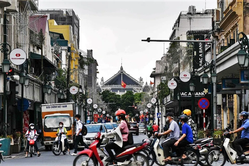 Motorists wearing face masks as a preventive measure against the spread of the Covid-19 coronavirus travel along a busy traffic intersection in Hanoi on 13 May 2020. (Manan Vatsyayana/AFP)