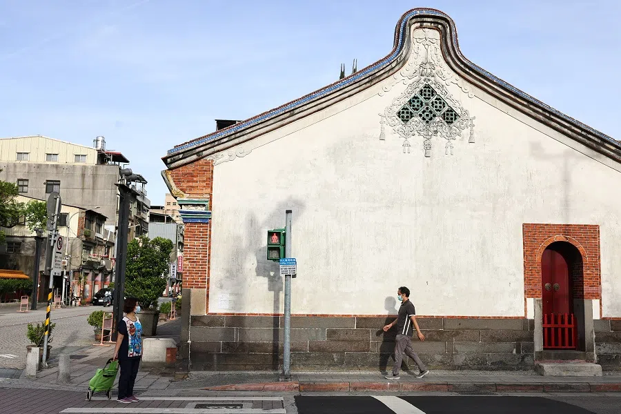 People wearing protective face masks walk past a temple in Taipei on 16 July 2021. (Ann Wang/Reuters)
