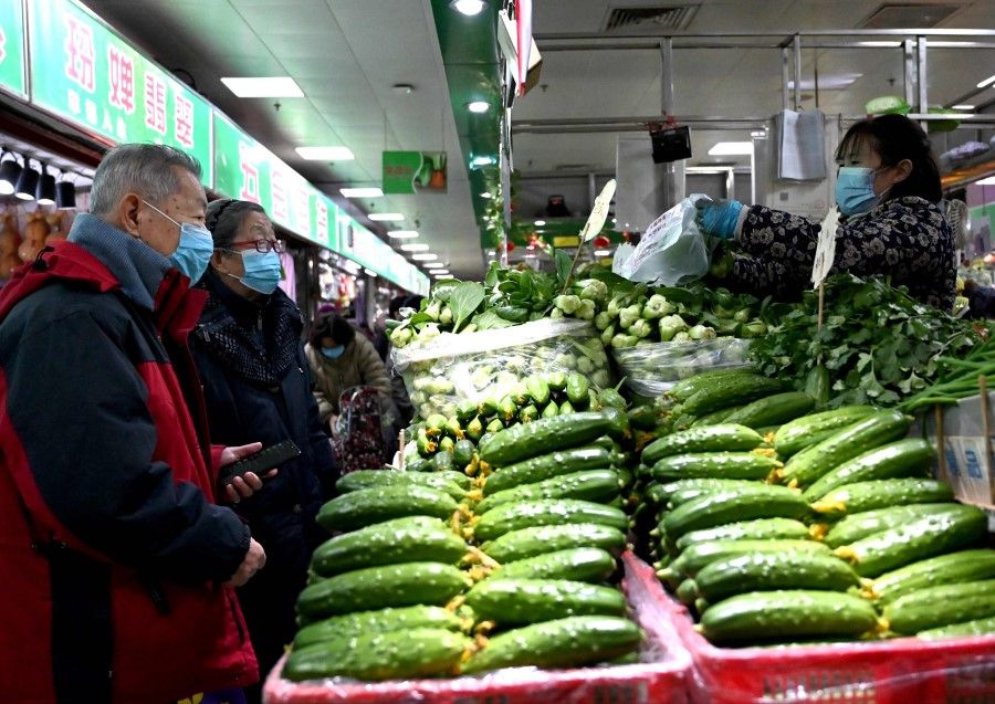 People buy vegetables at a market in Beijing on 17 January 2022. (Noel Celis/AFP)