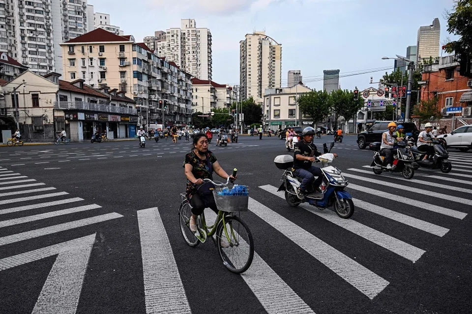 People ride bicycles and scooters in Shanghai’s Jing’an district on 26 August 2024.  (Hector Retamal/AFP)