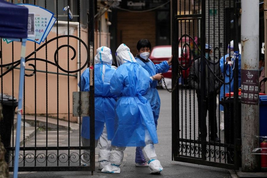 Workers in protective suits walk to a closed residential area during lockdown, amid the Covid-19 pandemic, in Shanghai, China, 9 May 2022. (Aly Song/Reuters)