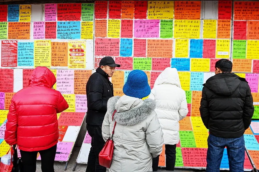 This photo taken on 27 February 2024 shows people checking job postings at a recruitment fair in Qingdao, in eastern China's Shandong province. (AFP)