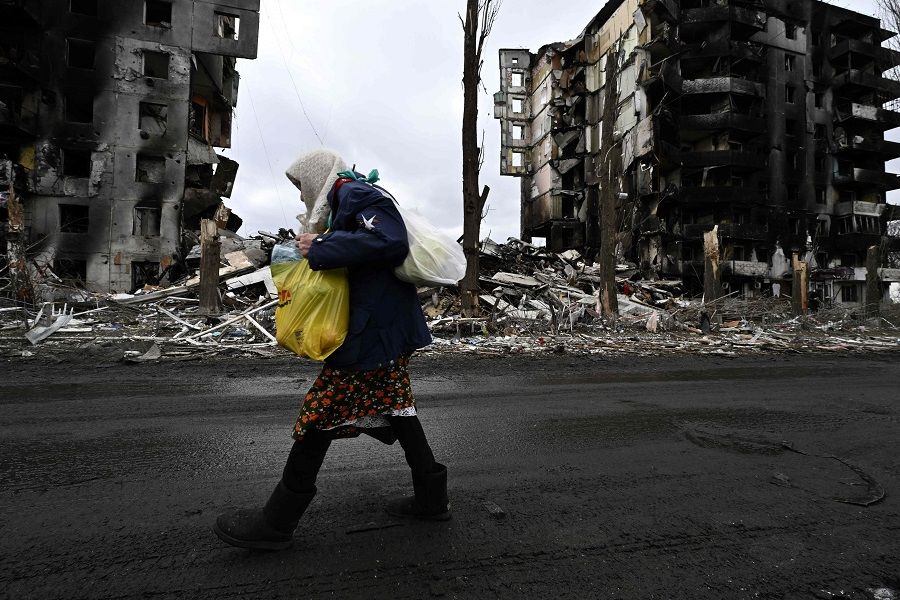 An woman walks in front of destroyed buildings in the town of Borodianka on 6 April 2022, about 30 miles northwest of the Ukrainian capital Kyiv. (Genya Savilov/AFP)