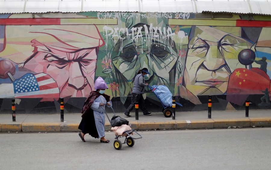 Women walk past a graffiti depicting US President Donald Trump, the Pachamama (Mother Earth) and Chinese President Xi Jinping, in El Alto, Bolivia, 16 October 2020. (Ueslei Marcelino/Reuters)