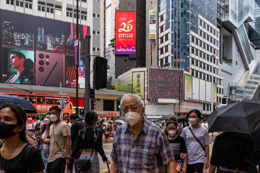 Pedestrians walk past a banner marking the 25th anniversary of Hong Kong's return to Chinese rule in Hong Kong, China, 1 July 2022. (Billy H.C. Kwok/Bloomberg)