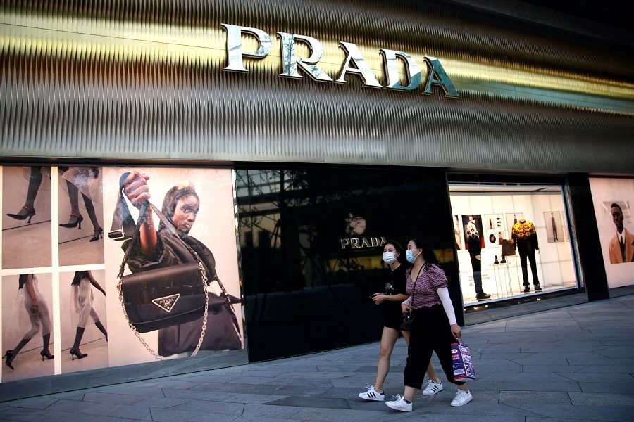 People wearing face masks walk past a store of Italian luxury brand Prada at a shopping complex in Beijing, China, 19 September 2020. (Tingshu Wang/File Photo/Reuters)