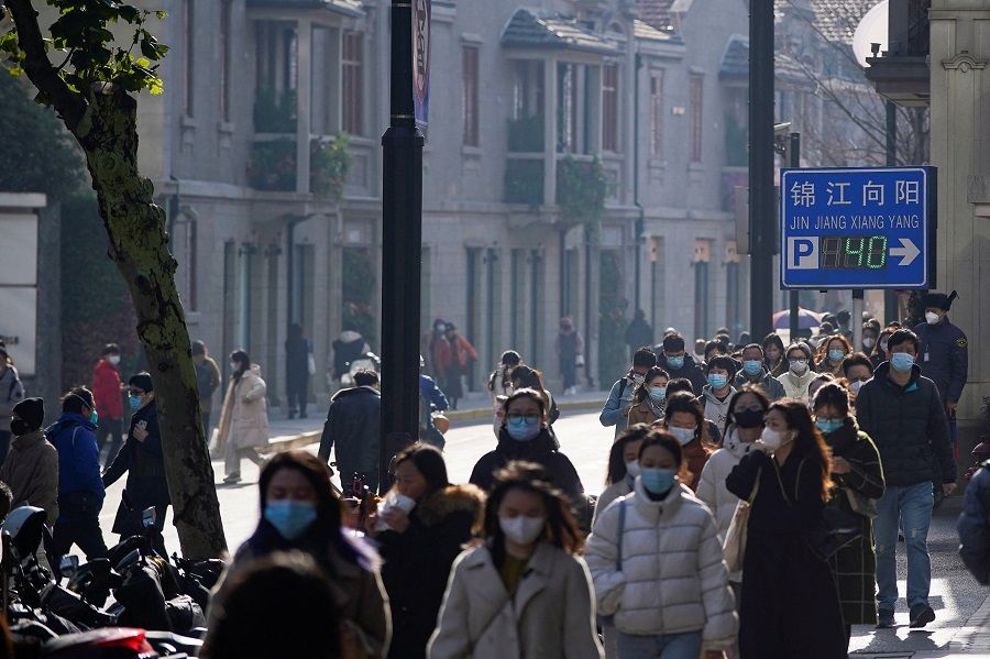 People wearing face masks walk on a street in Shanghai, China, 13 December 2022. (Aly Song/Reuters)