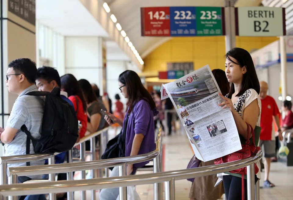 A woman reads Lianhe Zaobao at a bus interchange in Singapore. (SPH Media)