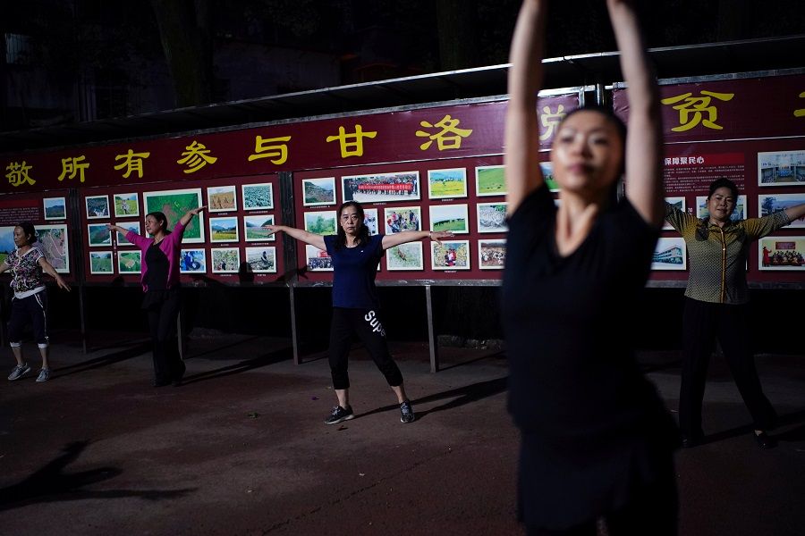 People dance in front of a billboard in praise of people who worked for the poverty alleviation of the county, at a square near the government building in Ganluo county, Liangshan Yi Autonomous Prefecture, Sichuan province, China, 9 September 2020. (Tingshu Wang/Reuters)
