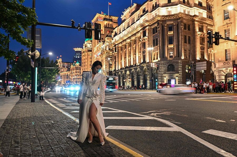This photo taken on 25 May 2021 shows a woman posing for a picture on the Bund in Shanghai, China. (Hector Retamal/AFP)