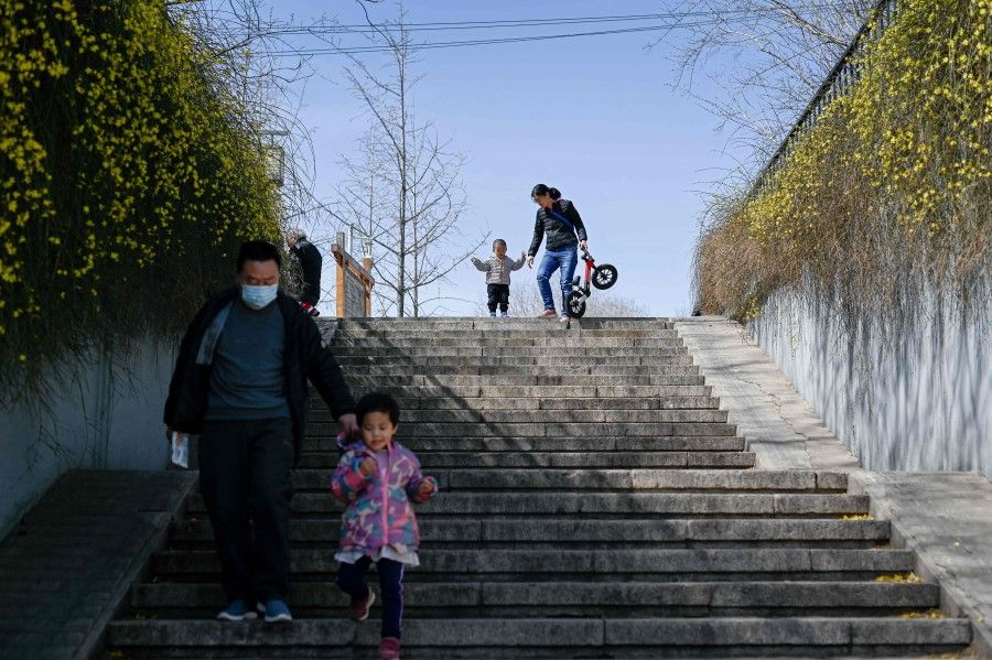 People walk down a flight of steps under blue skies in Beijing on 16 March 2021. (Wang Zhao/AFP)
