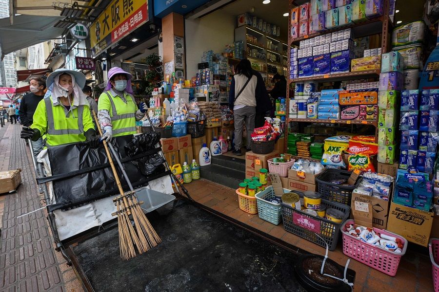 Cleaners walk past shops on a street in the town of Sheung Shui near the border of mainland China in Hong Kong on 4 January 2023. (Peter Parks/AFP)