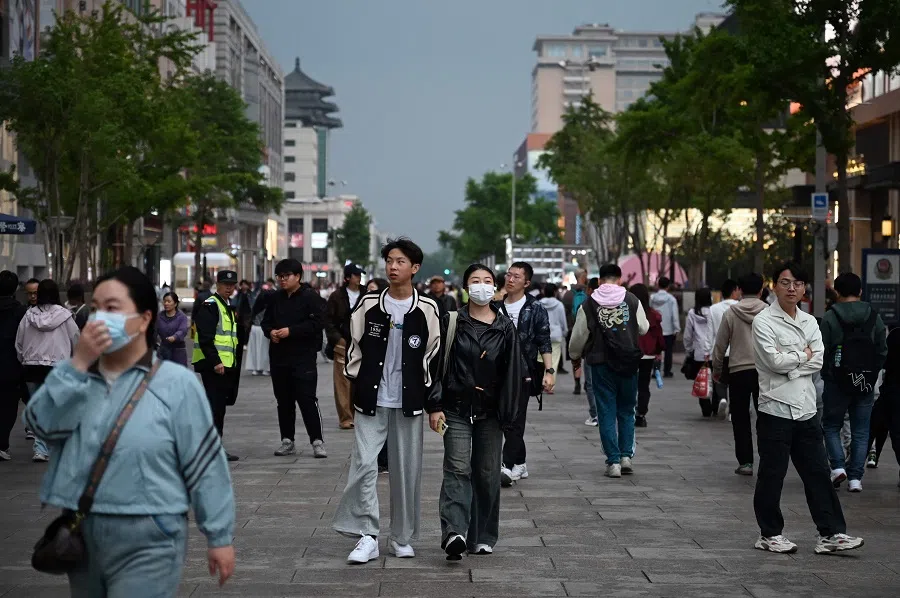 People walk at the Wangfujing shopping street in Beijing on 5 May 2025, the last day of a five-day national May Day holiday. (Greg Baker/AFP)