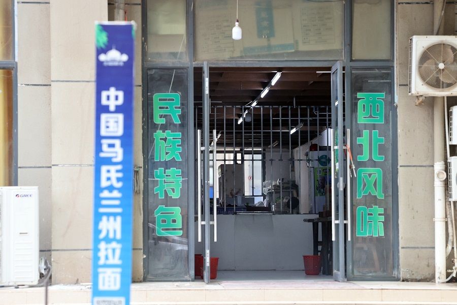 A Lanzhou noodle shop in Chinatown open to the public, with iron grilles demarcating spaces for visitors and compound residents.