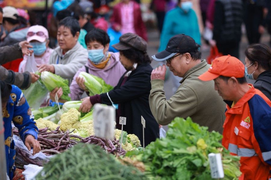 People buy vegetables at a market in Shenyang in China's northeastern Liaoning province on 14 October 2021. (STR/AFP)