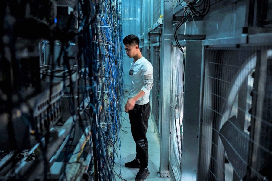 This photo taken on 1 April 2021 shows a worker adjusting cryptocurrency mining rigs at a cryptocurrency farm in Dujiangyan in China's southwestern Sichuan province. (STR/AFP)