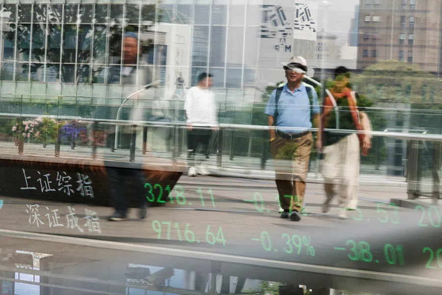 An electronic board shows Shanghai and Shenzhen stock indices as people walk on a pedestrian bridge at the Lujiazui financial district in Shanghai, China, on 11 April 2025.