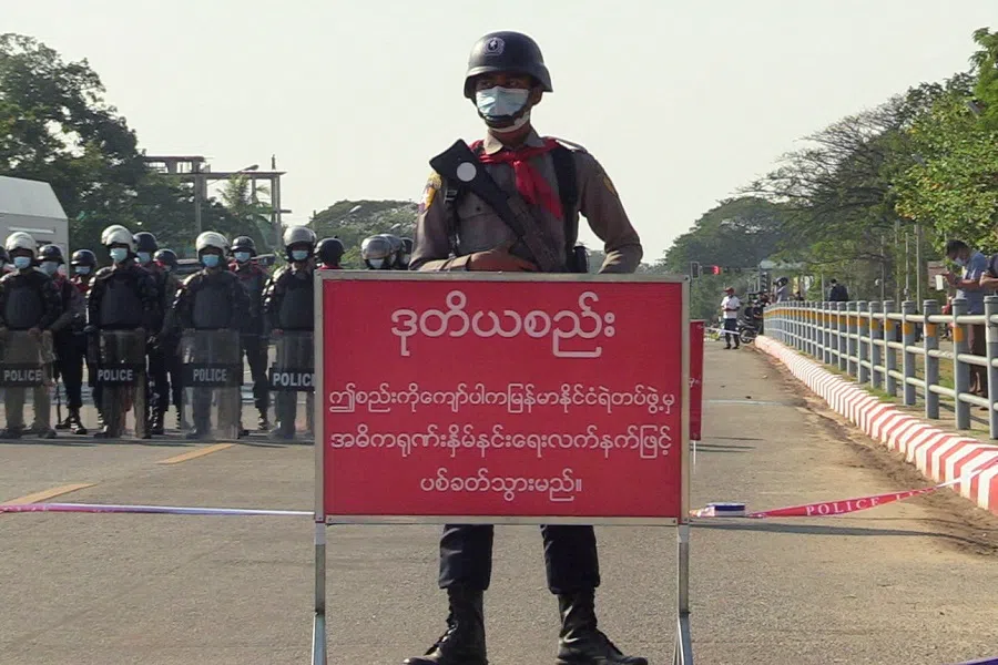 A policeman stands behind a banner reading "if this line is crossed, Myanmar police force will fire with live ammunition" during protests against the military coup and to demand the release of elected leader Aung San Suu Kyi, in Nay Pyi Taw, Myanmar, 8 February 2021. (Stringer/File Photo/Reuters)