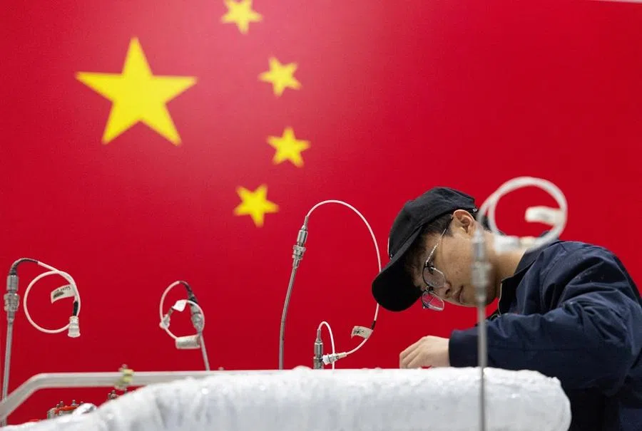 An engineer works on a rocket engine at the assembly hall with a national flag of China displayed in the background at China’s private rocket company LandSpace's factory in Huzhou, Zhejiang province, China, on 17 December 2025.  (Maxim Shemetov/Reuters)