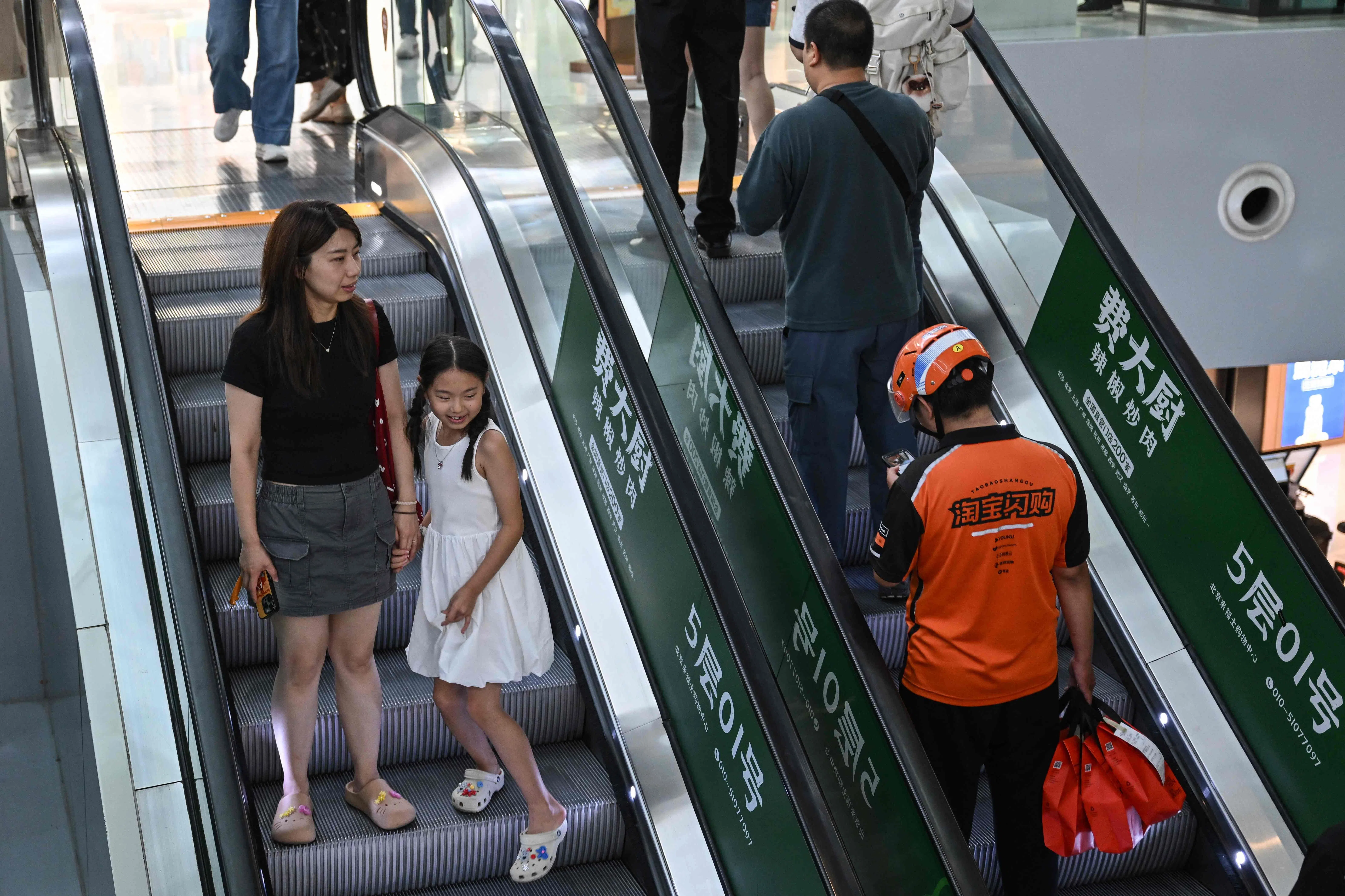 People use escalators in a shopping mall in Beijing on 2 August 2026.