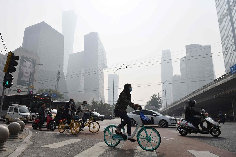 This file photo taken on 10 October 2020 shows people crossing a road on a polluted day in Beijing, China. (Greg Baker/AFP)