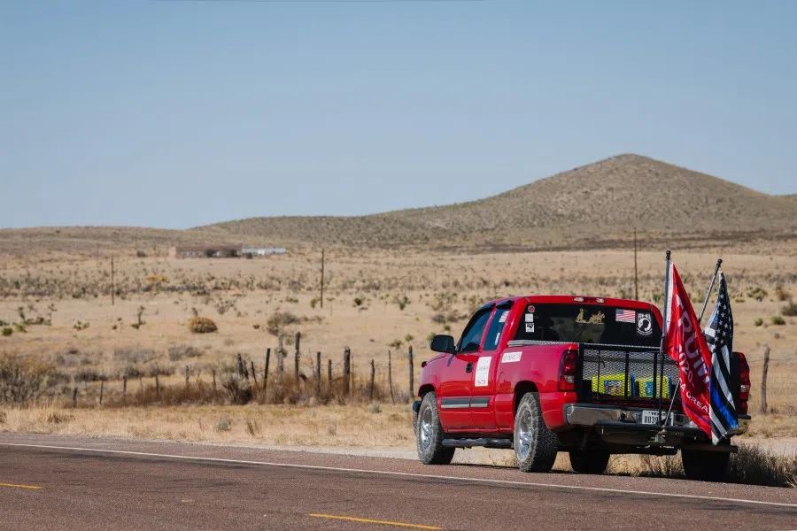 Thin Blue Line and Trump 2020 flags wave in the air across from a United States Border Patrol checkpoint at the Desert Haven Fire Rescue polling location east of El Paso in rural Hudspeth County, Texas on 3 November 2020. (Justin Hamel/AFP)