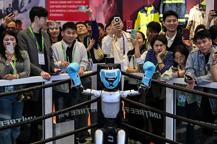 A remote-controlled robot by Unitree Robotics raises its arms at the corner of the ring during a robot boxing match at the Unitree Robotics stand during the 8th International Import Expo (CIIE) in Shanghai on 6 November 2025. (Hector Retamal/AFP)