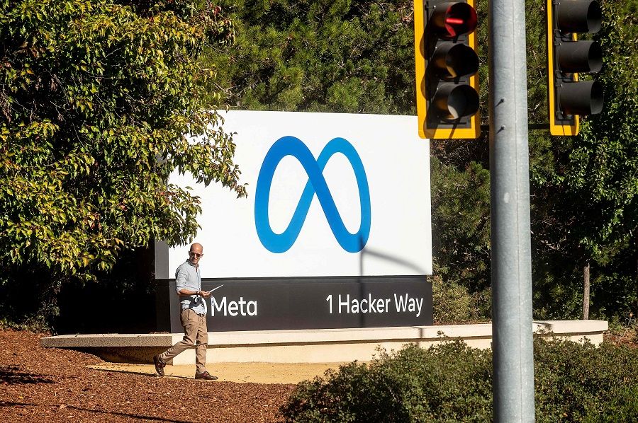 In this file photo taken on 28 October 2021, a man passes a newly unveiled logo for "Meta", the new name for Facebook's parent company, outside Facebook headquarters in Menlo Park, California, US. (Noah Berger/AFP)