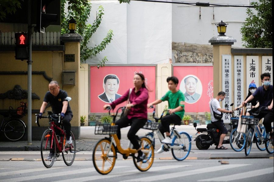 People pass by portraits of Chinese President Xi Jinping and late Chinese chairman Mao Zedong, in Shanghai, China, 31 August 2022. (Aly Song/Reuters)