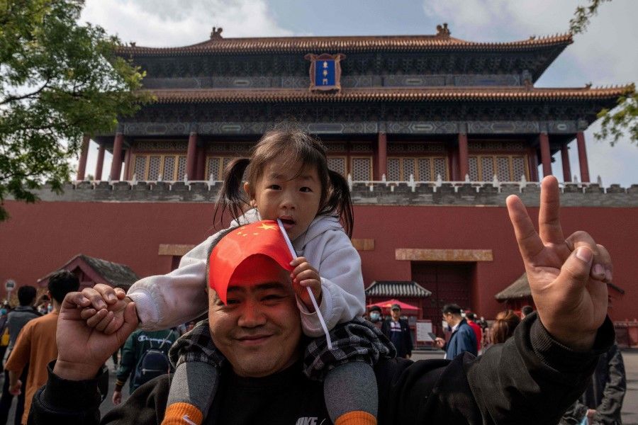 A girl sits on the shoulders of her father outside the Forbidden City during the national day marking the 71st anniversary of the People's Republic of China and the country's national "Golden Week" holiday in Beijing on 1 October 2020. (Nicolas Asfouri/AFP)