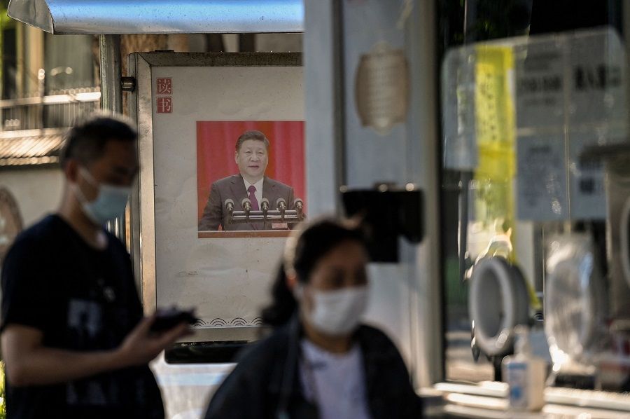 In this file photo taken on 31 August 2022, a propaganda poster showing China's President Xi Jinping is displayed on a bulletin board next to a Covid-19 swab collection site in Beijing, China. (Jade Gao/AFP)