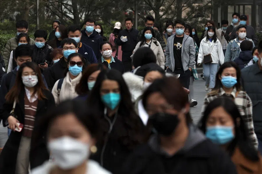 People walk on a street during morning rush hour in Beijing, China, 16 March 2022. (Tingshu Wang/Reuters)