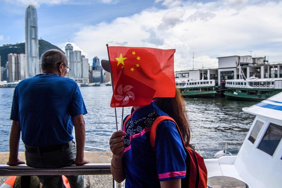 A member of a local community group holds Chinese and Hong Kong flags as she disembarks from a boat in Victoria Harbour on the 23rd anniversary of the city's handover from Britain in Hong Kong on 1 July 2020. (Anthony Wallace/AFP)